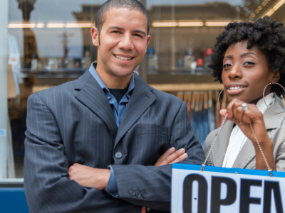Business owners showcasing an 'OPEN' sign, representing unsecured lines of credit and business loans for financial growth.
