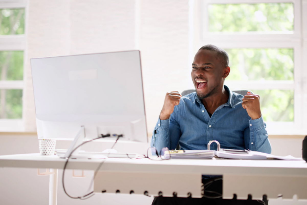 Man celebrating success at a desk, representing family business achievements and effective management strategies.