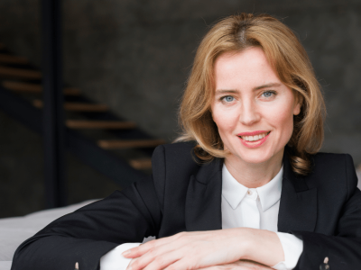 Professional woman smiling in a business setting, representing team building and collaboration activities.