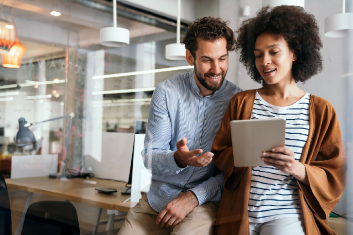 Business professionals discussing financial strategies while reviewing a tablet in a modern office setting.