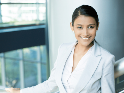 Professional woman smiling in a business setting, representing small business success and outsourcing strategies.