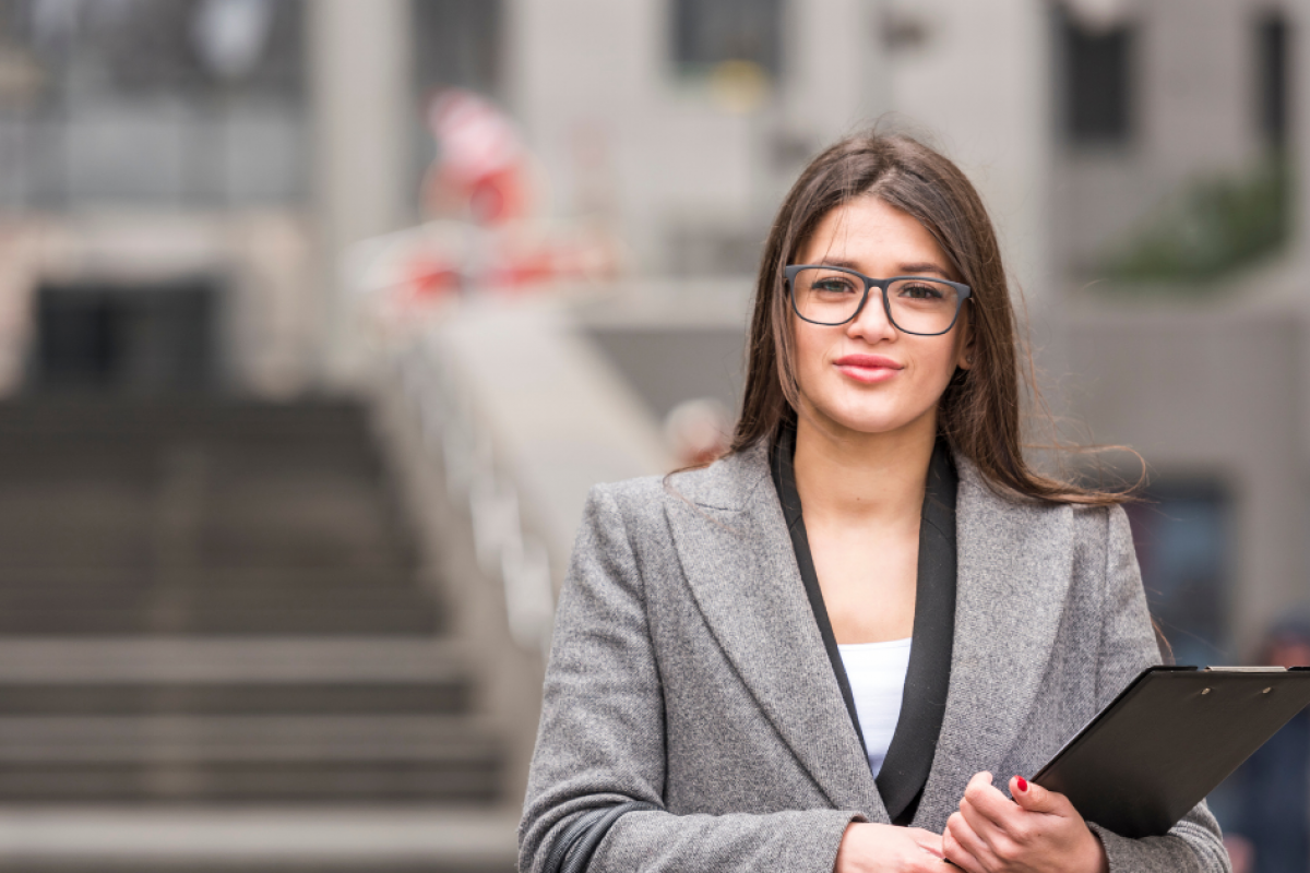 Professional woman holding a clipboard, embodying key traits of a great worker in a dynamic work environment.