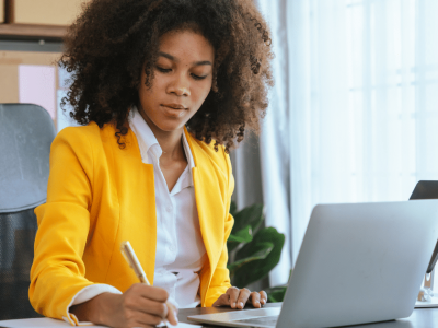Business owner writing notes while planning New Year’s resolutions for business growth and success.