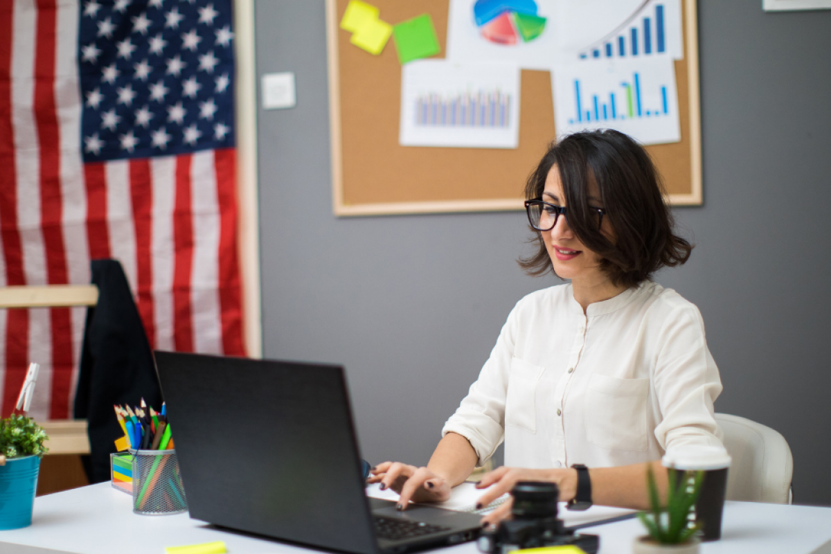 Businesswoman working on a laptop in an office with charts, emphasizing essential CEO qualities for leadership and success.