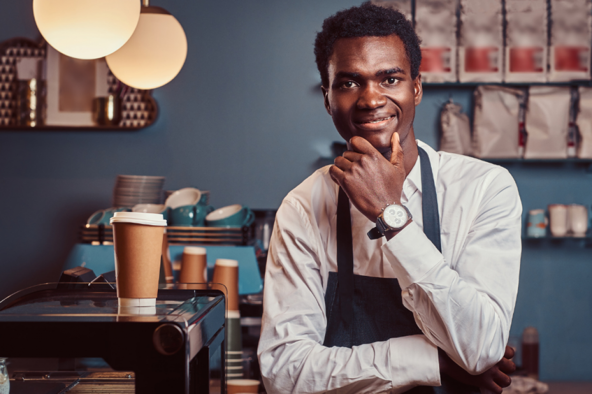 Smiling barista in a coffee shop, representing small business credit building and financing opportunities.