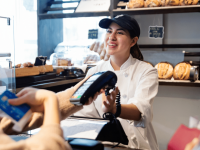 Business financing solutions for growth, featuring a cashier assisting a customer with payment in a bakery setting.