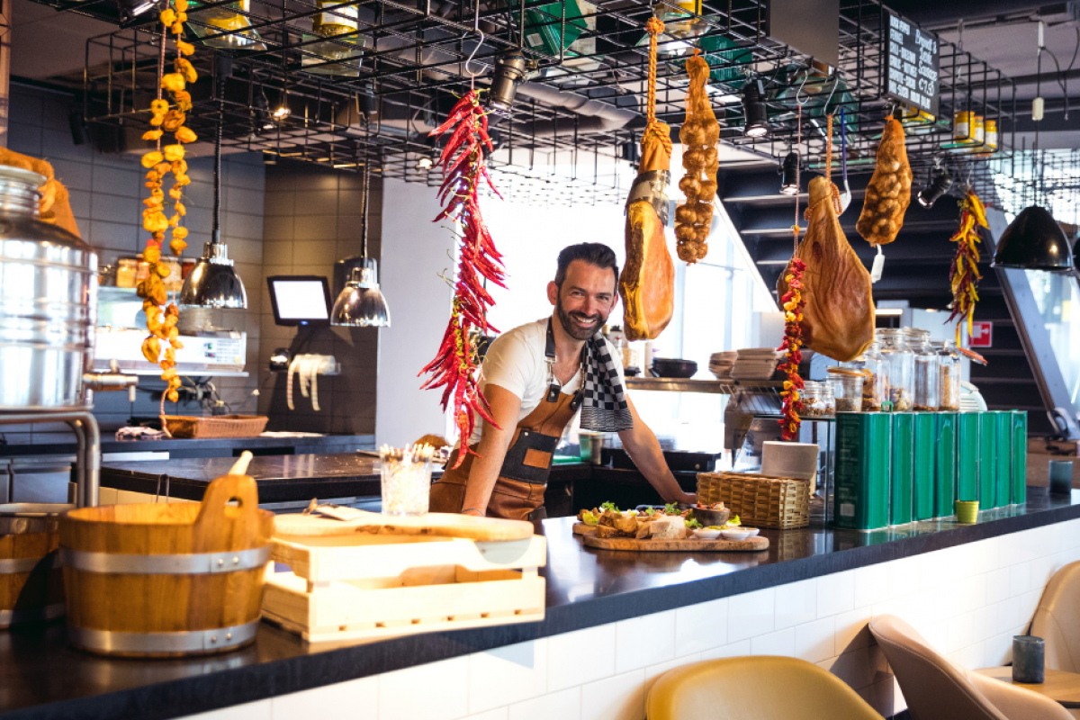 Small business owner in a modern restaurant, showcasing food and decor, highlighting financing options for growth.