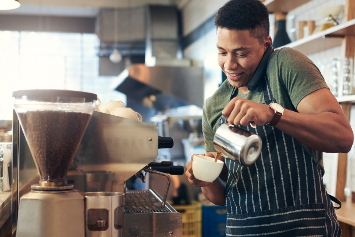 Barista pouring coffee in a cafe, highlighting small business operations in the food and beverage industry.