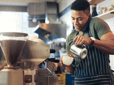 Barista pouring coffee in a cafe, highlighting small business operations in the food and beverage industry.