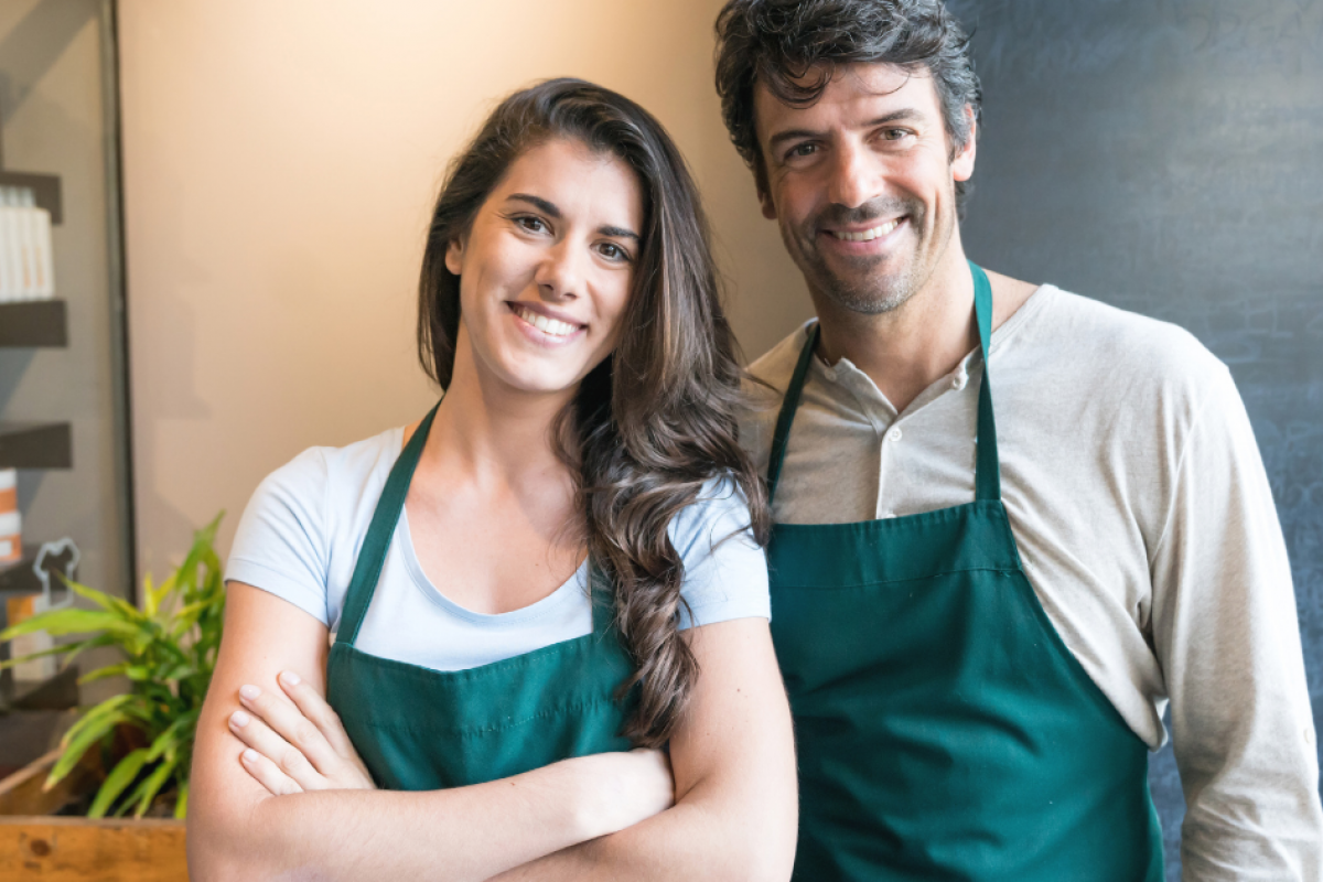 Smiling business owners in aprons, representing small business finance solutions and overcoming money problems.