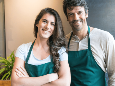 Smiling business owners in aprons, representing small business finance solutions and overcoming money problems.
