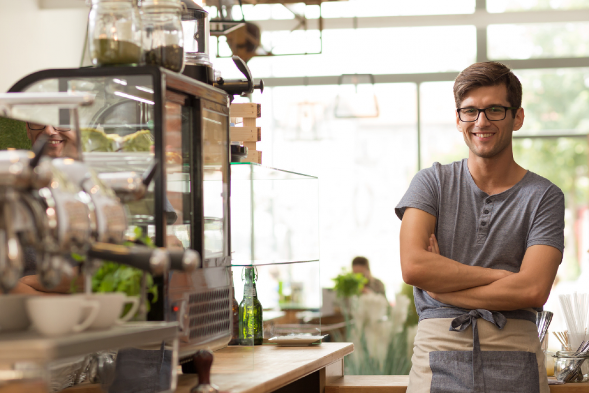 Small business owner smiling in a cafe, highlighting financial success and avoiding pitfalls in 2024.