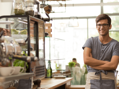 Small business owner smiling in a cafe, highlighting financial success and avoiding pitfalls in 2024.