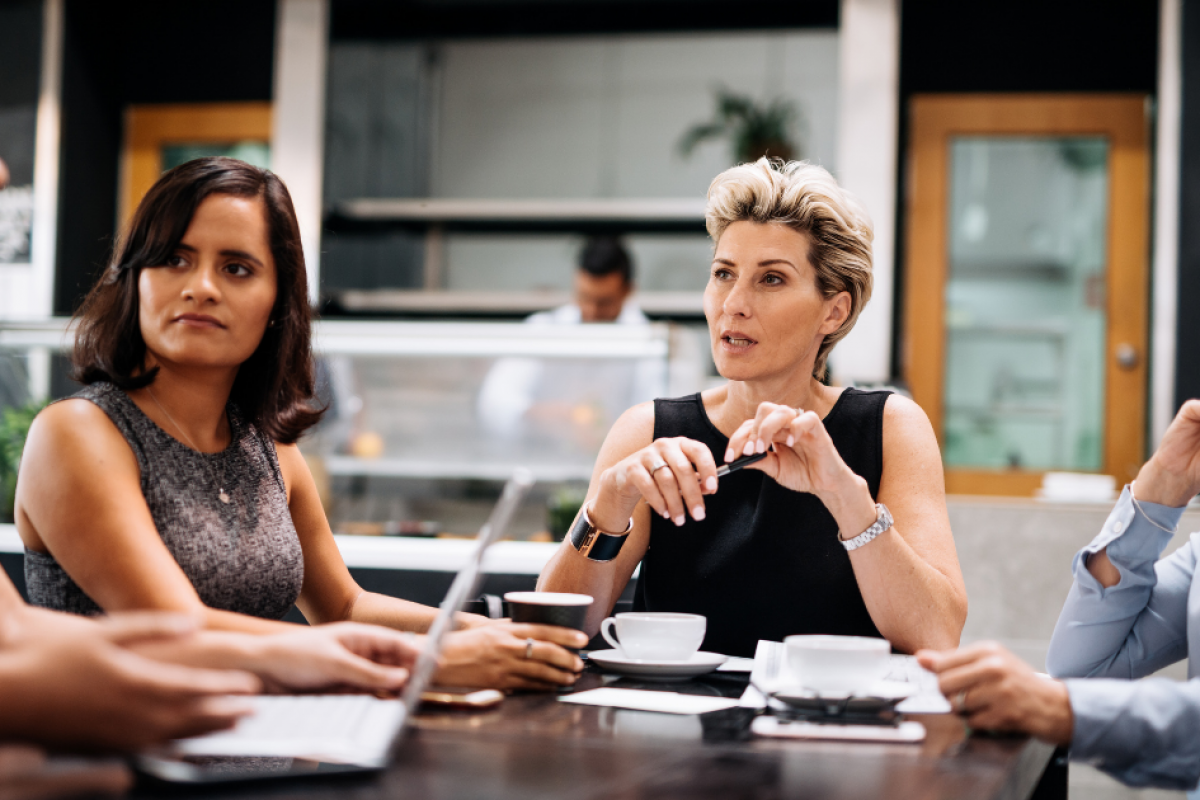 Women discussing smart investing strategies over coffee in a modern workspace, highlighting collaboration and finance.