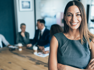 Businesswoman smiling confidently in a modern office, highlighting business relocation strategies for profit maximization.
