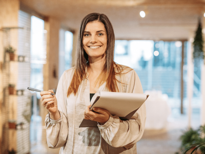 Smiling woman holding a notepad and pen, representing franchise growth and unsecured loans for bad credit.