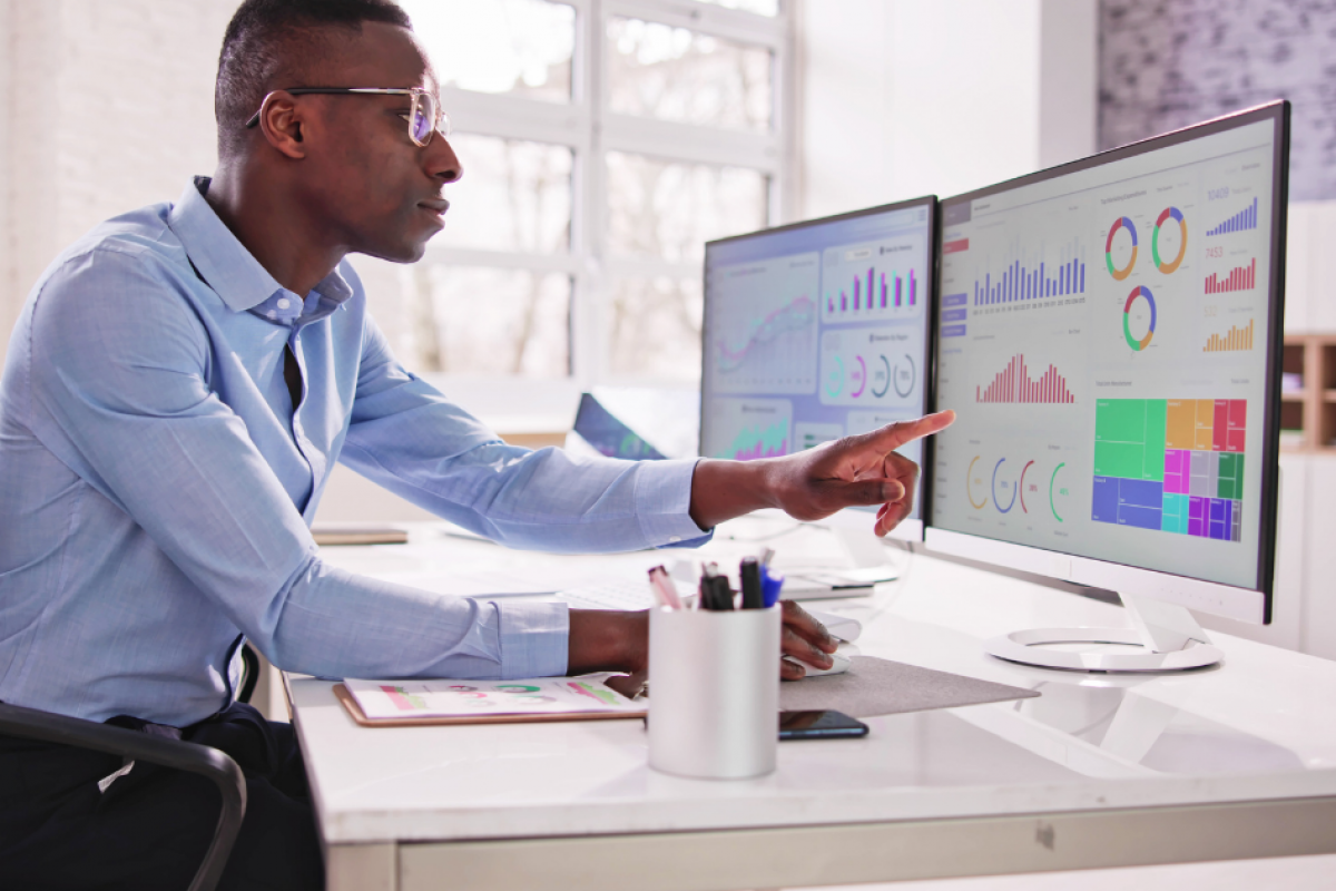 Business professional analyzing financial data on dual monitors, highlighting insights for effective decision-making.