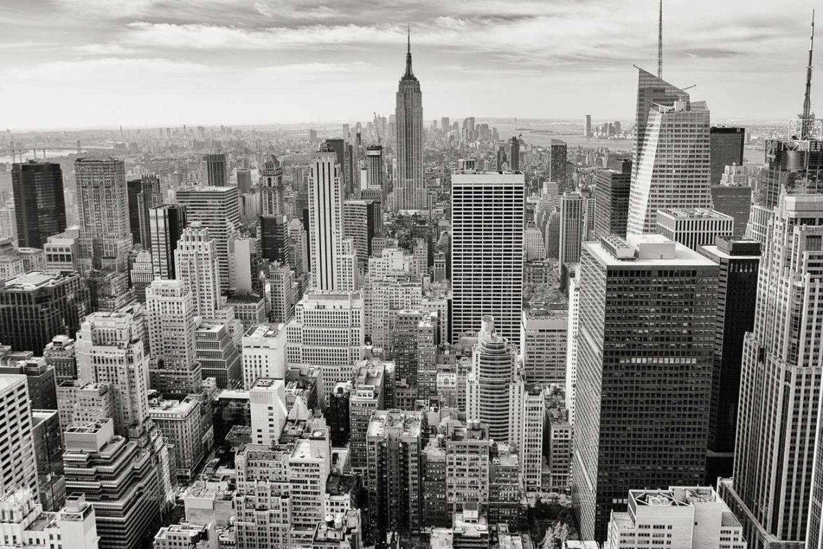 Black and white aerial view of New York City skyline featuring iconic skyscrapers and the Empire State Building.