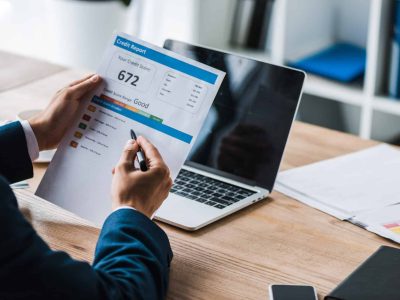 cropped view of man holding pen near paper with credit report letters