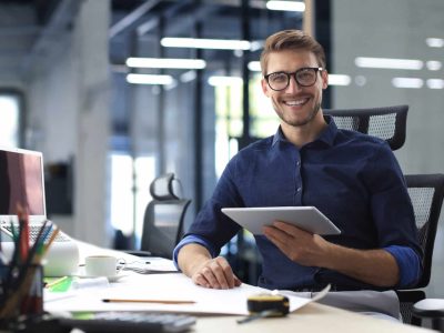 Young modern business man working using digital tablet while sitting in the office