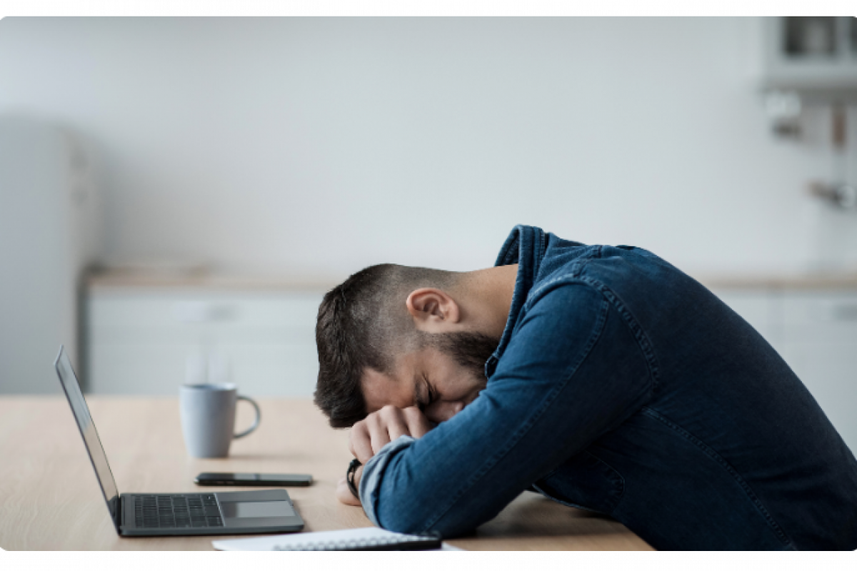 Stressed businessman with head down on desk, highlighting the challenges of the business loan application process.