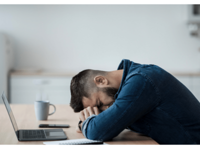 Stressed businessman with head down on desk, highlighting the challenges of the business loan application process.