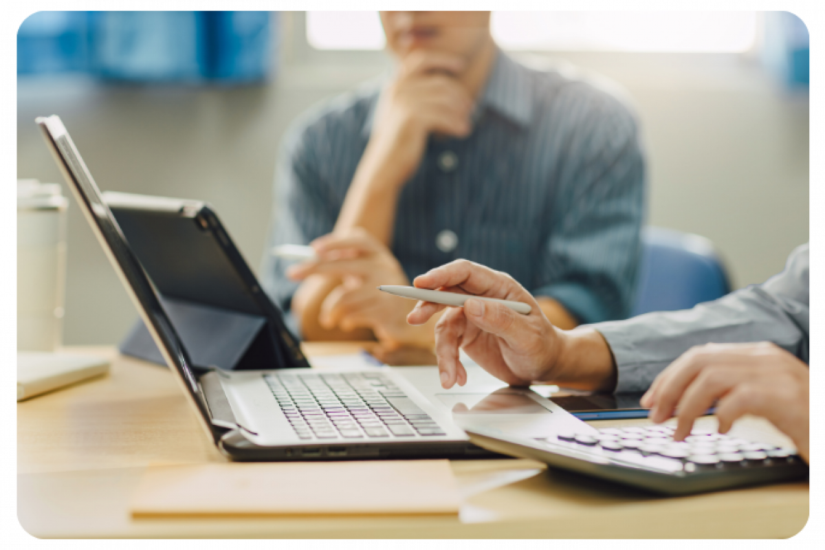 Business professionals discussing financing options with a laptop and calculator, focusing on small business loans.