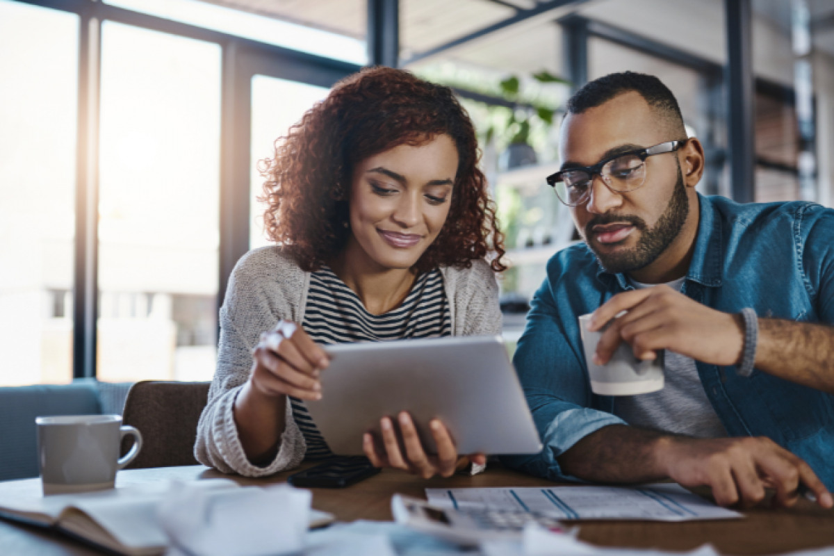 Couple reviewing financial information on a tablet, exploring new credit opportunities and FICO score improvements.