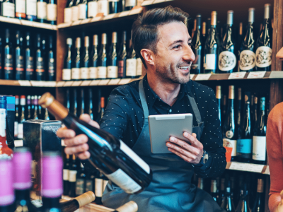 Liquor store owner assisting a customer with business loans, showcasing inventory and customer service in a vibrant store.