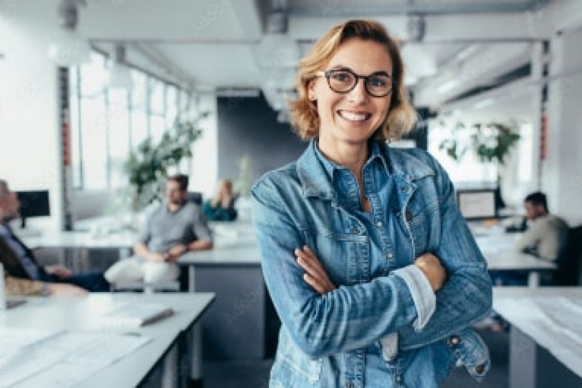 Smiling businesswoman in a modern office, representing HVAC financing solutions and employee empowerment for summer growth.