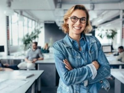 Smiling businesswoman in a modern office, representing HVAC financing solutions and employee empowerment for summer growth.
