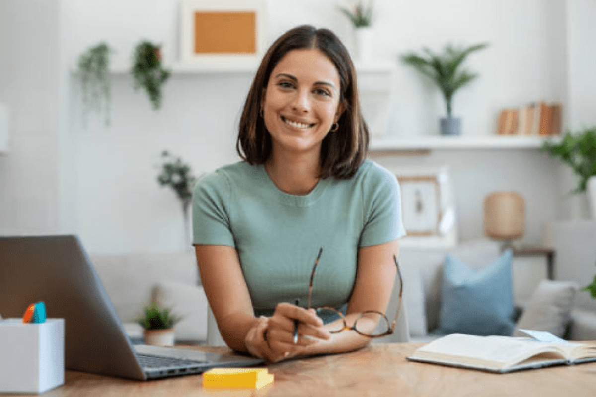 Smiling woman at a desk with a laptop, representing business financing and line of credit solutions.