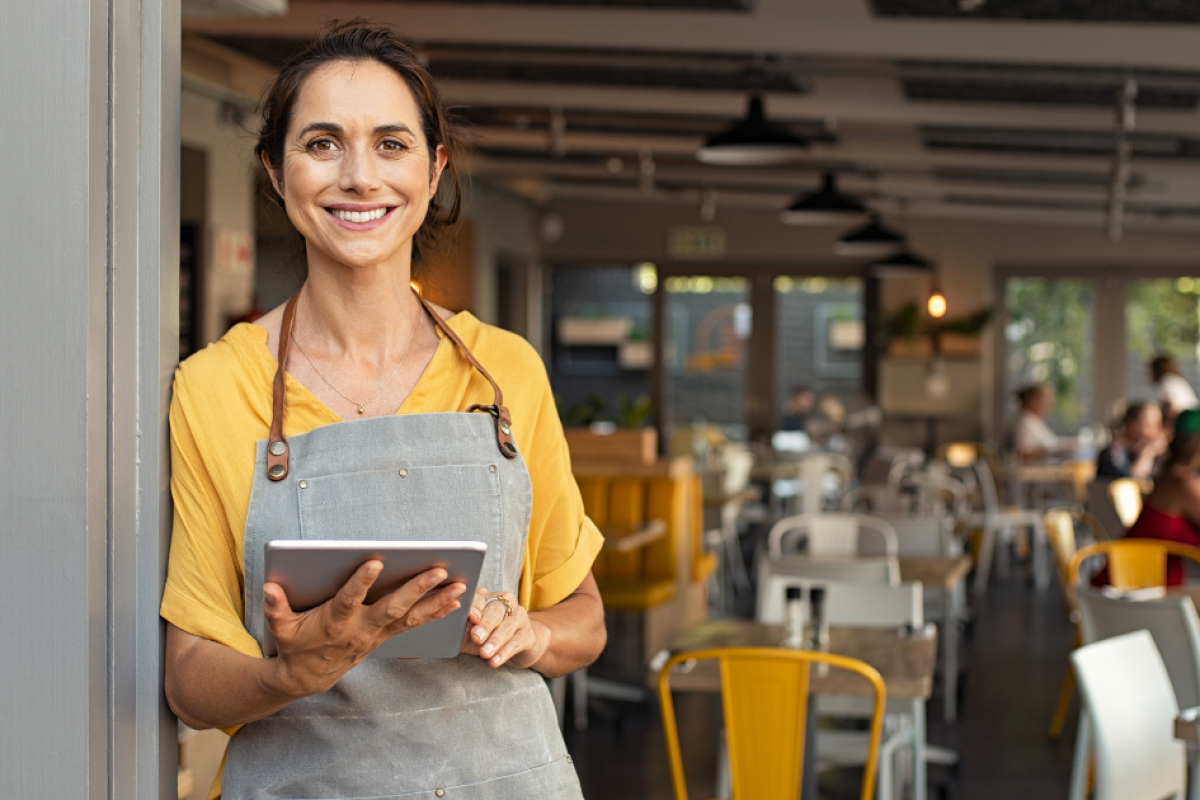 Smiling small business owner in a cafe, showcasing summer strategies for success and employee appreciation.